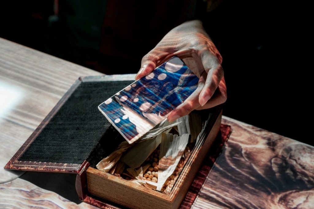 Hand opening a box with scented items, part of a sensory dining experience before the meal begins.