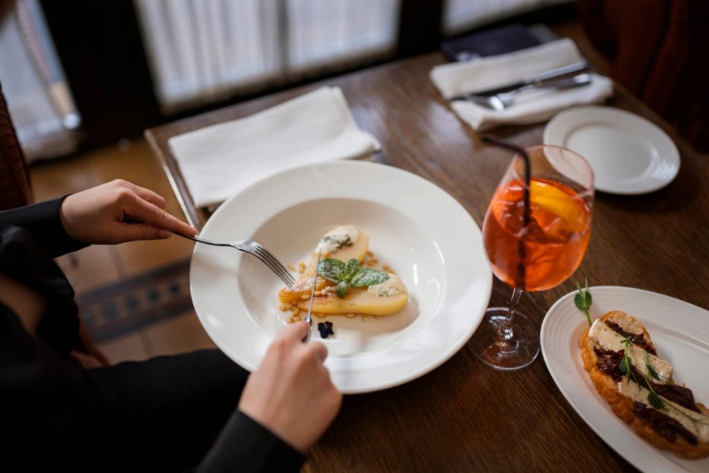 Person eats simple plated dish with drink, showing relaxed modern fine dining experience in Bali.