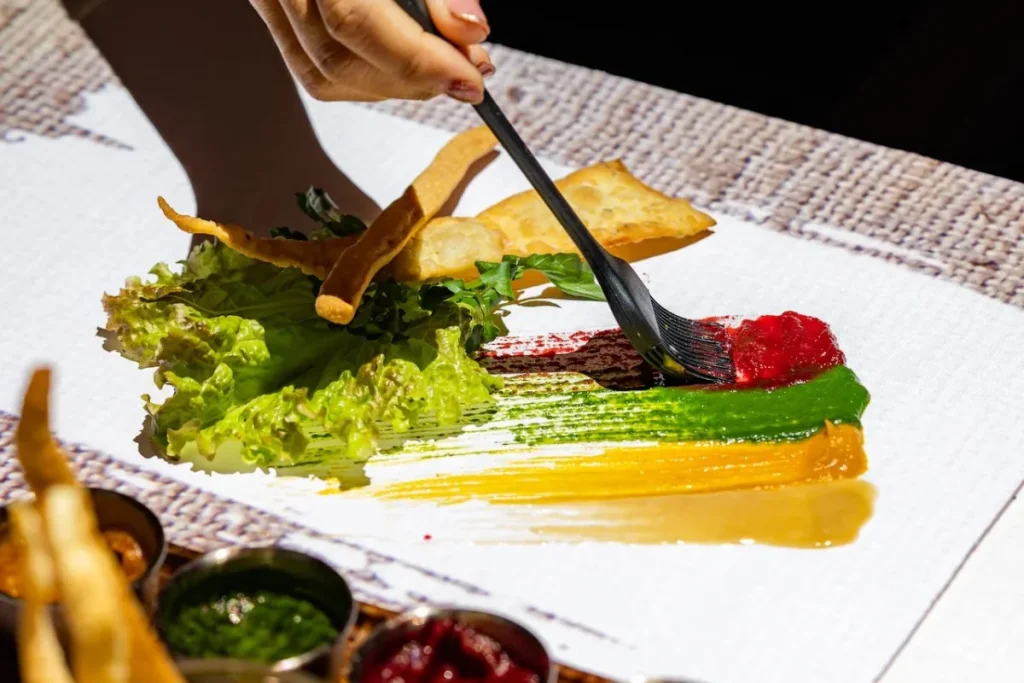 Chef creating colorful food presentation art on a dining table at a Bali restaurant experience.