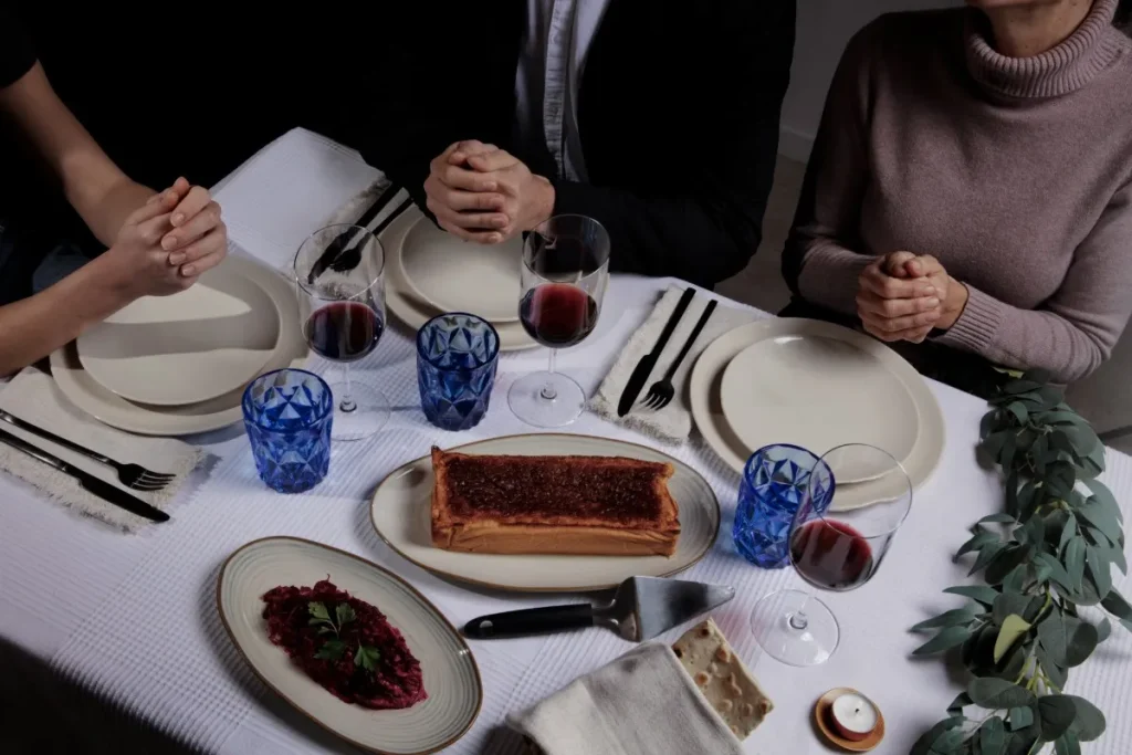 People sitting at a formal dining table with food and table settings.