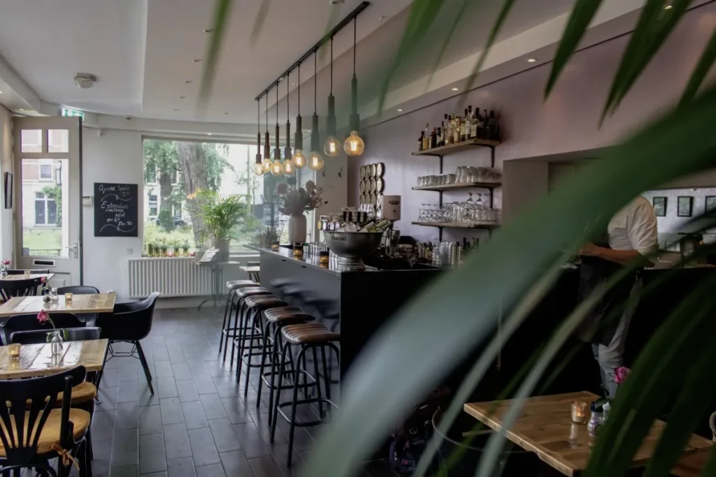 Modern cafe interior with bar seating, tables, and a welcoming atmosphere for visitors.