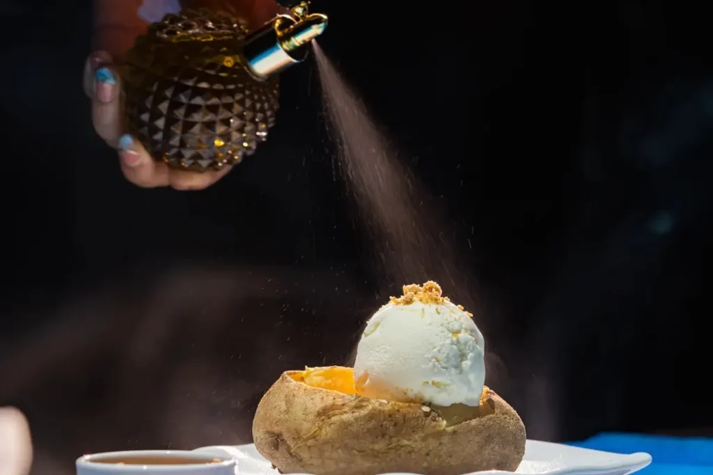Chef sprays aroma over a dessert, showing a molecular gastronomy technique served in a Bali restaurant.